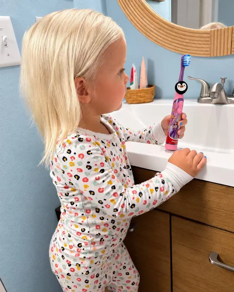 Truthbrush Tracker with penguin skin clipped onto a child's toothbrush