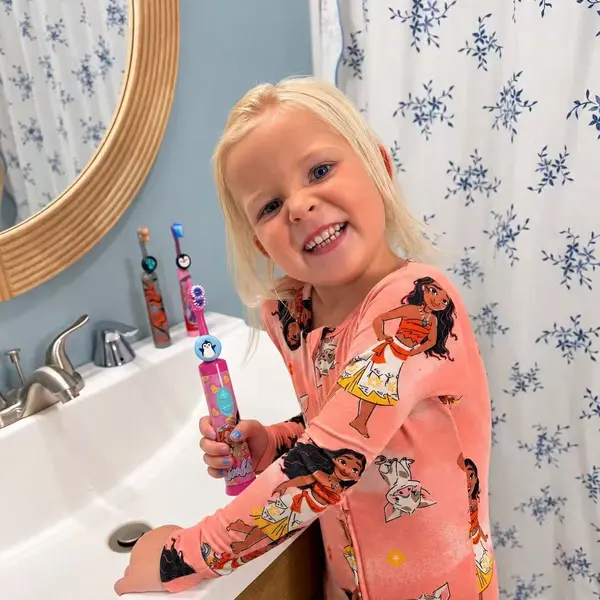 Child brushing at the sink with three Truthbrush-equipped toothbrushes