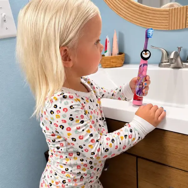Truthbrush Tracker with penguin skin clipped onto a child's toothbrush