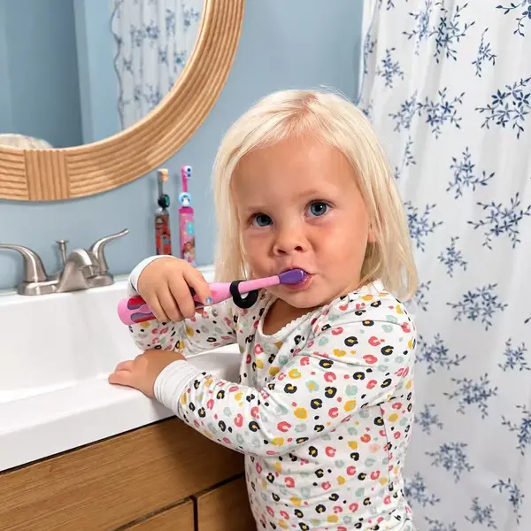 Toddler brushing her teeth with a Truthbrush Tracker clipped to her toothbrush