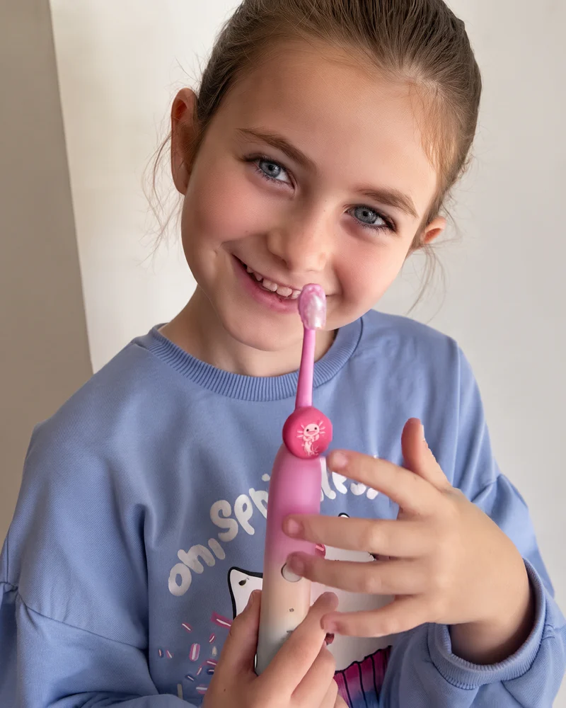 Girl holding a pink electric toothbrush with an axolotl-skin Truthbrush Tracker