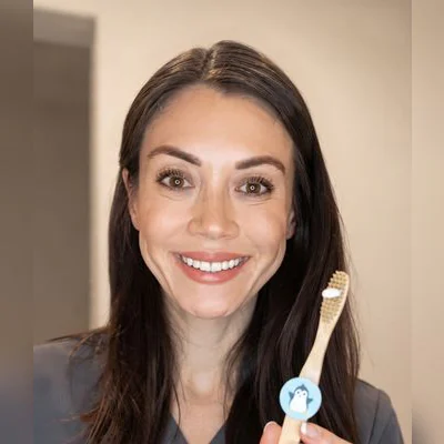 Adult holding a bamboo toothbrush with a penguin-skin Truthbrush Tracker