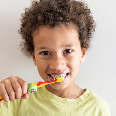 Boy brushing his teeth with a Truthbrush Tracker clipped to his toothbrush