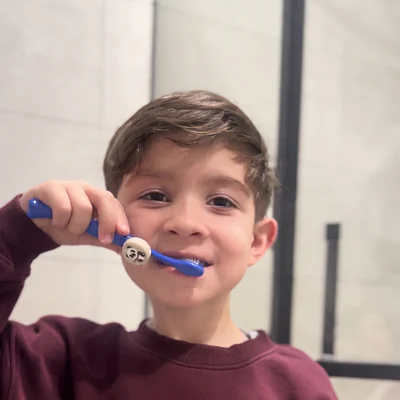 Boy brushing his teeth with a panda-skin Truthbrush Tracker on his toothbrush