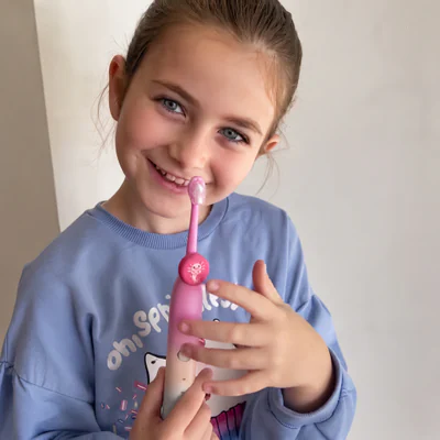 Girl holding a pink electric toothbrush with an axolotl-skin Truthbrush Tracker