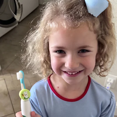 Girl holding an electric toothbrush with a bunny-skin Truthbrush Tracker