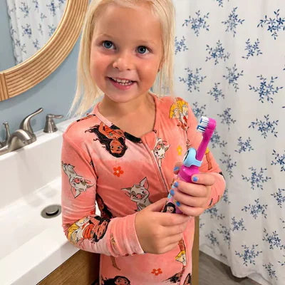 Girl at the bathroom sink holding a toothbrush with a Truthbrush Tracker