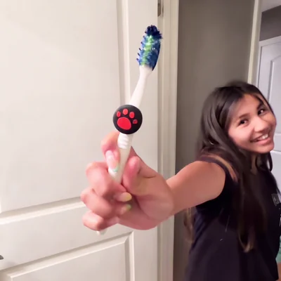Older child holding up a toothbrush with a paw-print Truthbrush Tracker